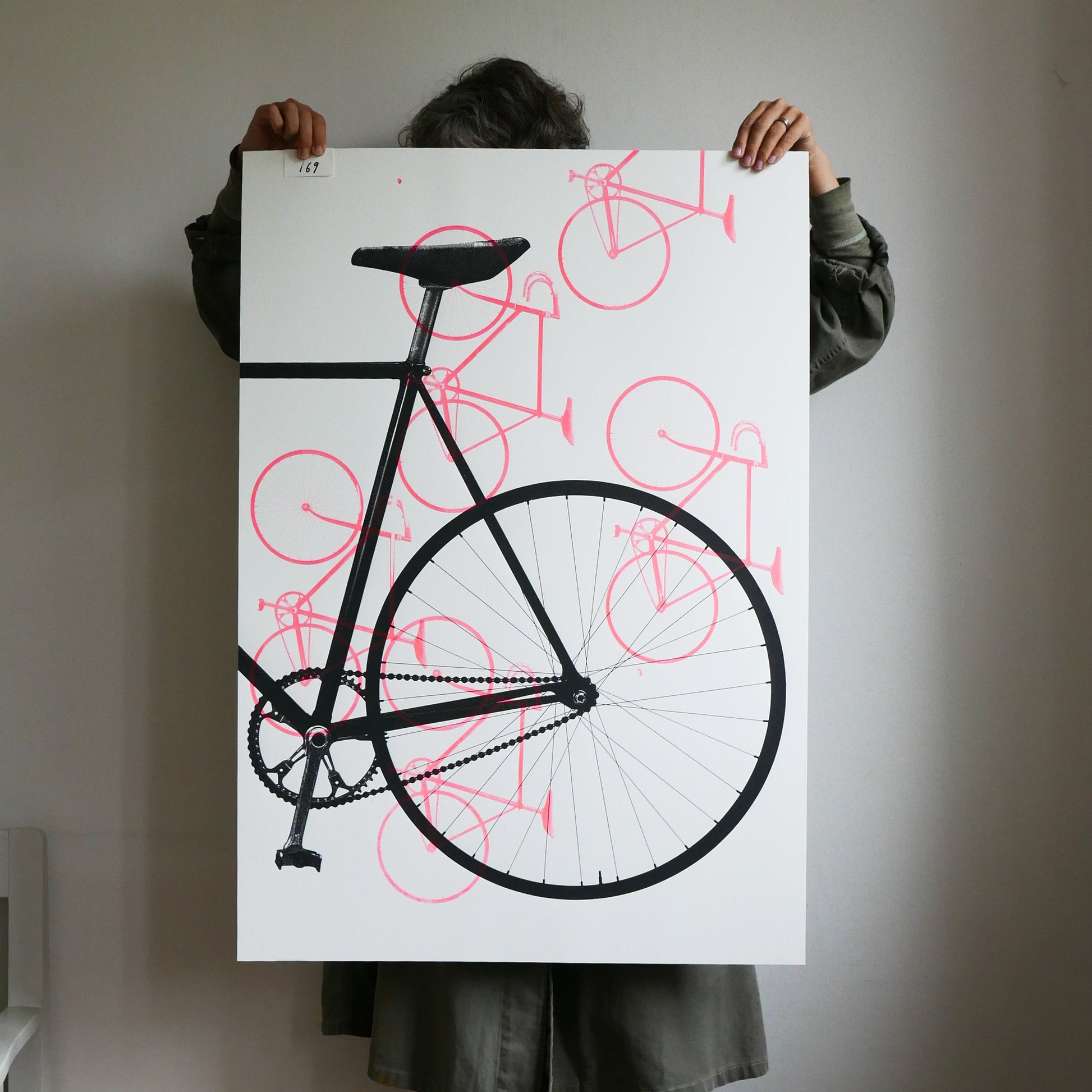 Person holding a large poster of a black bicycle with red outlines against a white background.