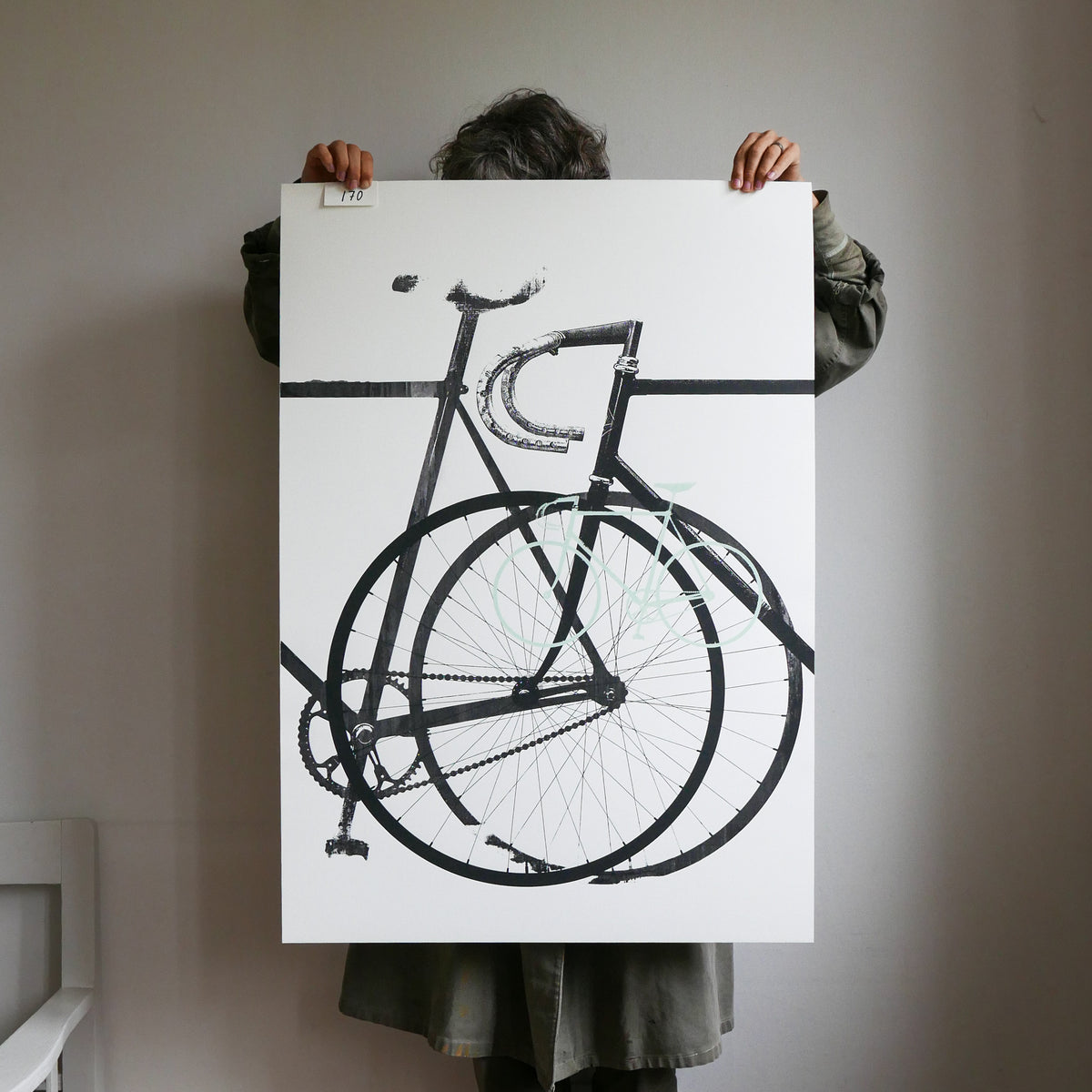 Person holding a large black and white bicycle illustration on a white background